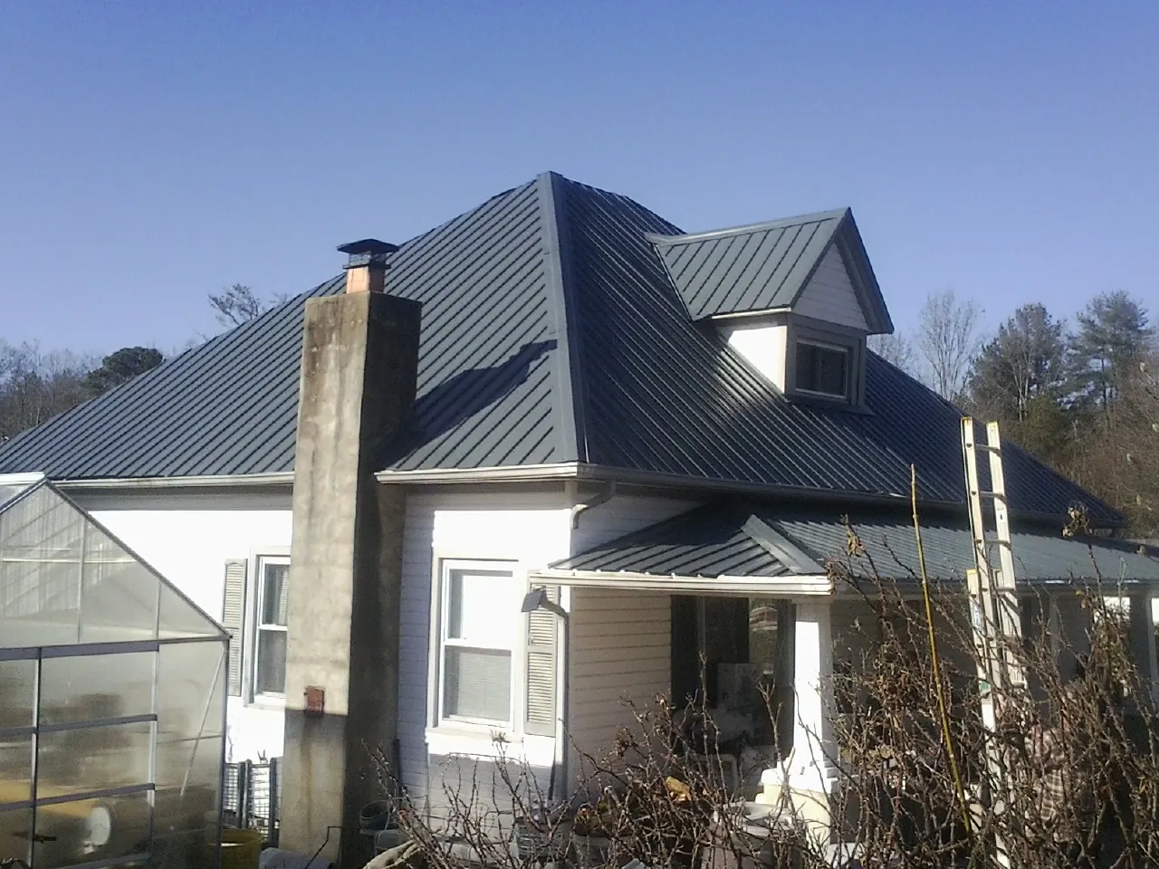 Dark blue standing seam metal roof on a white farmhouse with dormer — Slate & Tile Roof Repair by Roofing Brothers in Cassatt