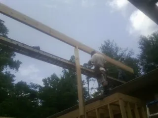 Carpenter setting a ridge beam over a new addition frame — Ice Dam Removal by Roofing Brothers in Cassatt