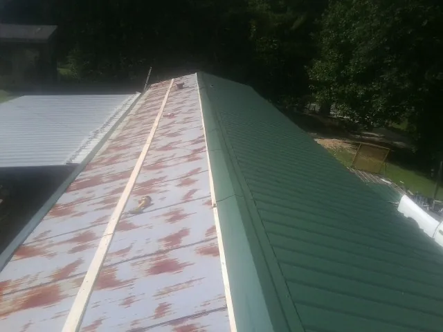 Old rusted panels beside newly installed green metal roofing — Wind Damage Roof Repair by Roofing Brothers in Cassatt