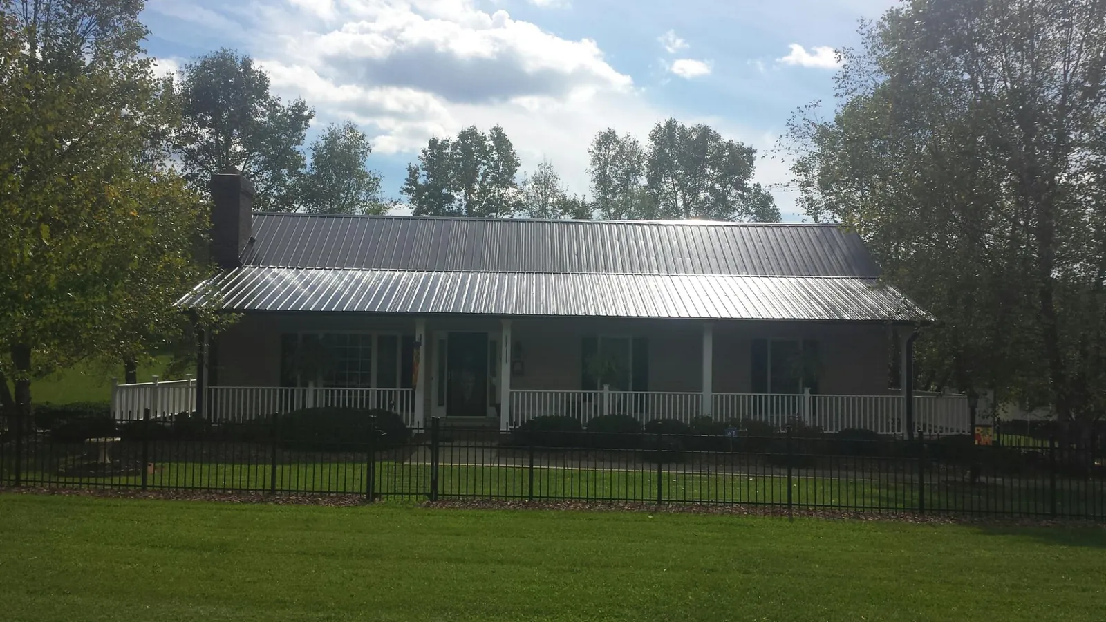 Gray metal roof on a brick ranch with a full width front porch — Gutter Guard Installation work by our crew in Cassatt