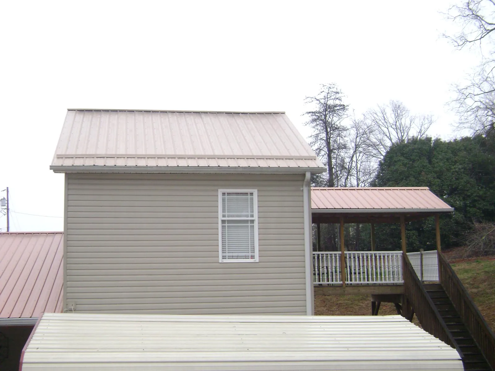 Tan metal roofs on a two story addition and attached porch, from a Roof Replacement job in Cassatt